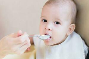 mamá alimenta su nueve meses bebé a hogar foto