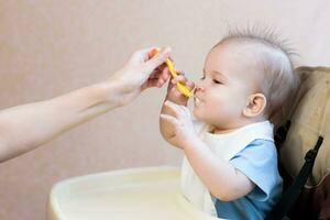 Mother gives baby food from a spoon photo