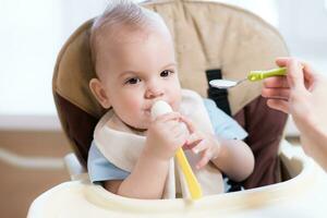 Mother gives baby food from a spoon photo