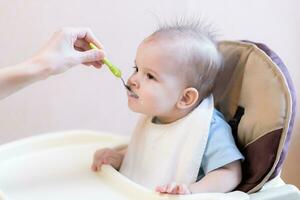Mother gives baby food from a spoon photo