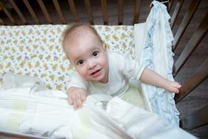 the baby is in the crib and looking up photo