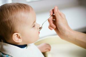 Mother gives baby food from a spoon photo