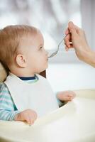 Mother gives baby food from a spoon photo