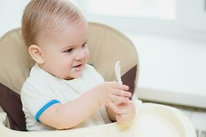 baby holding a spoon in his mouth and laughs photo