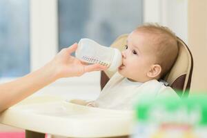 Mother feeds baby from a bottle of milk photo