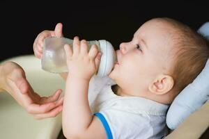 Mother feeds baby from a bottle of milk photo