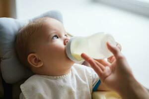 Mother feeds baby from a bottle of milk photo