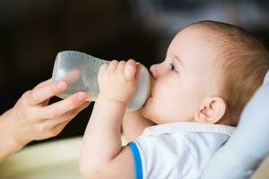 Mother feeds baby from a bottle of milk photo