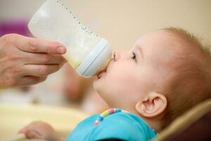 Mother feeds baby from a bottle of milk photo