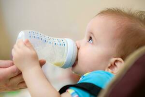 Mother feeds baby from a bottle of milk photo