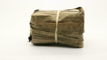 Indonesian rice cake covered in banana leaves on a white background photo