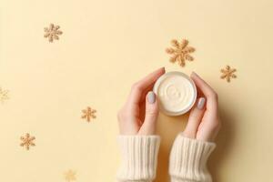 Winter season skin care cosmetics concept. First person top view photo of woman's hands in knitted sweater small cream jar and snowflakes on isolated pastel beige background. generative ai.