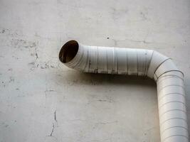 Cylindrical curved pipe on a concrete wall photo