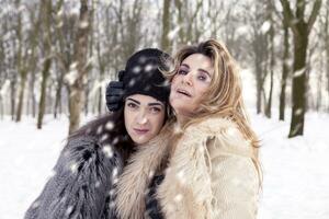 mamá y hija abrazando cada con amor en el nieve foto