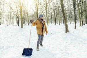 young man shoveling snow near a small wood photo