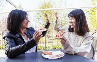 young multi-ethnic female friends eating a pizza outdoors photo