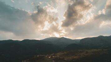 panoramic view of a valley surrounded by hills at sunset with the sun obscured by clouds photo