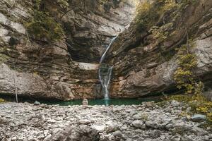 wonderful small waterfall that forms a pond of emerald water in a forest photo