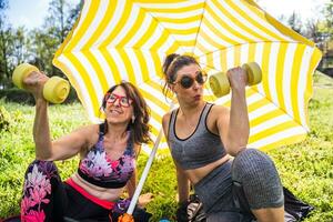 beautiful middle aged women in sportswear relaxing under a beach umbrella photo