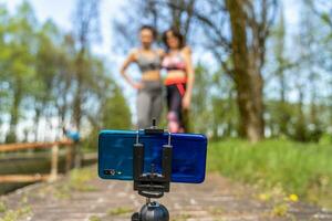 runner mature women taking a selfia with  smartphone on a tripod outdoor photo