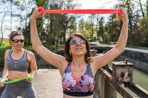 beautiful middle aged women doing exercises outdoors with a resistance band photo