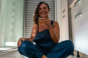 image of a beautiful middle aged woman drinking a cocktail sitting in her apartment photo