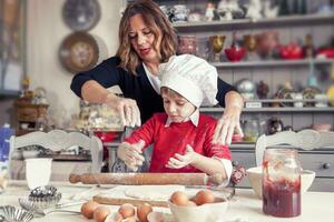 mom helping her son prepare sweet food photo