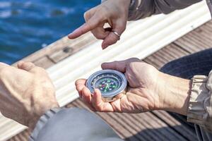 beautiful mature couple sitting on the dock looks at compass photo