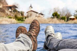 de cerca de pies en excursionismo botas en frente un lago foto
