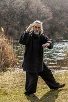 mature man practicing Tai Chi discipline outdoors photo