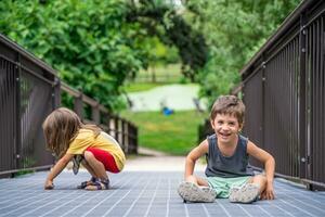 pair of male and female twins having fun on the metal grate of a bridge in a green park photo