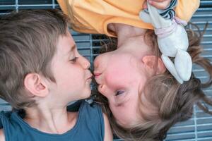 portrait of twins male and female are kissing lying on a metal grate photo