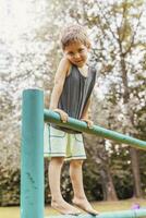 smiling cute child climbing on a metal railing in a public park photo