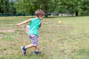 smiling cute child playing with an old tennis racket in a public park photo