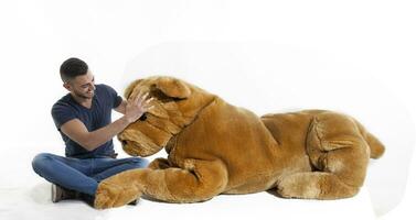 young adult sitting with a giant toy dog on white background photo