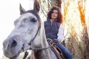 amazona paseos su caballo a el país carreteras en otoño foto