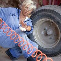 mechanical mature female inflates the tire of the tractor photo