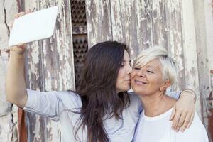 madre y adulto hija tomar un selfie al aire libre foto