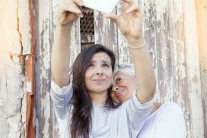 madre y adulto hija tomar un selfie al aire libre foto