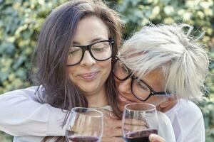 madre y adulto hija saboreo vino sentado al aire libre foto