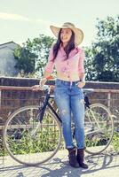 bonito joven mujer en bicicleta en un país la carretera foto