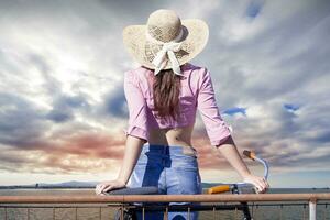 pretty girl with hat from the back looks at sea horizon photo