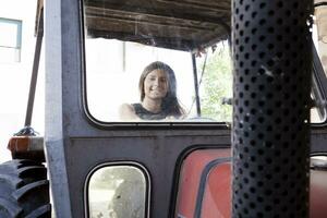 hermosa joven mujer sentado en un tractor foto