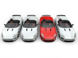 Red sports car stands out amongs white sports cars - top down view photo