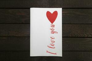 Valentines card. White paper card with red heart and inscription I Love you. photo