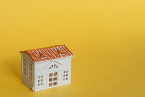 Miniature toy house on yellow. Real Estate concept. Copy space photo