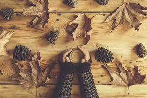 taza de té en hembra manos. otoño hojas terminado de madera mesa. otoño todavía vida concepto. caer, otoño comida y beber. parte superior vista. foto
