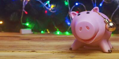 Festive Finance. Piggy bank and xmas toys against decorated christmas tree. Christmas finances concept. photo