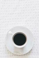 Morning coffee. A cup of coffee. Hot black coffee on the pure white knitted tablecloth photo