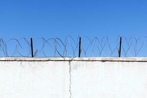 Jail wall. Highly protected prison wall with barbed wire fence photo